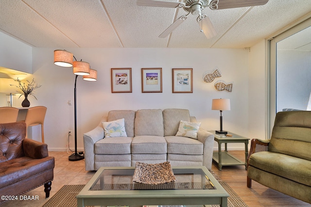 living room featuring light hardwood / wood-style floors, ceiling fan, and a textured ceiling