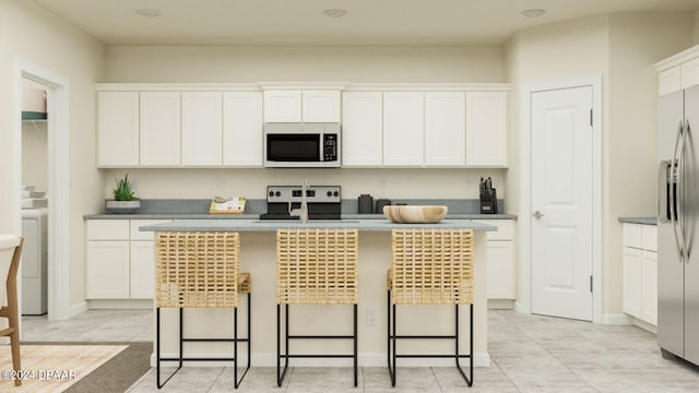 kitchen with a breakfast bar, white cabinets, and a center island with sink