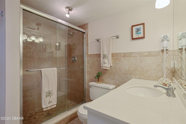 4435 S Atlantic Ave Unit 414, Ponce Inlet, FL 32127 - bathroom featuring toilet, vanity, a stall shower, a textured ceiling, and tile walls