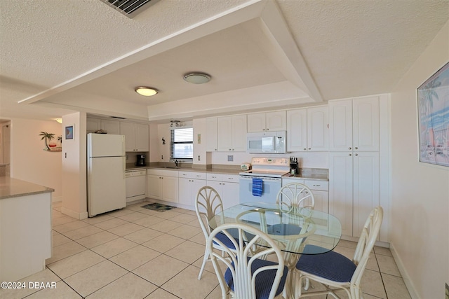 kitchen featuring a textured ceiling, sink, light tile patterned floors, white cabinetry, and white appliances