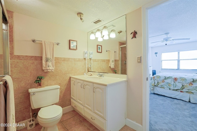 bathroom with ceiling fan, a textured ceiling, vanity, tile patterned floors, and tile walls