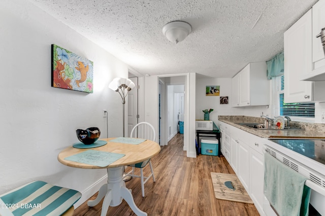 545 Cannon St, Daytona Beach, FL 32114 - kitchen with a textured ceiling, white appliances, white cabinetry, light wood-type flooring, and light countertops