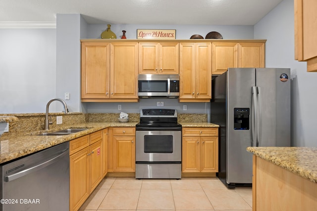 kitchen with light tile patterned floors, sink, crown molding, light stone countertops, and appliances with stainless steel finishes