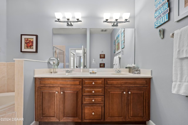 bathroom featuring vanity, tiled bath, and a notable chandelier