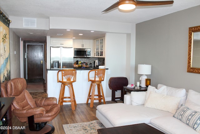 living room featuring a textured ceiling, ceiling fan, and dark wood-type flooring