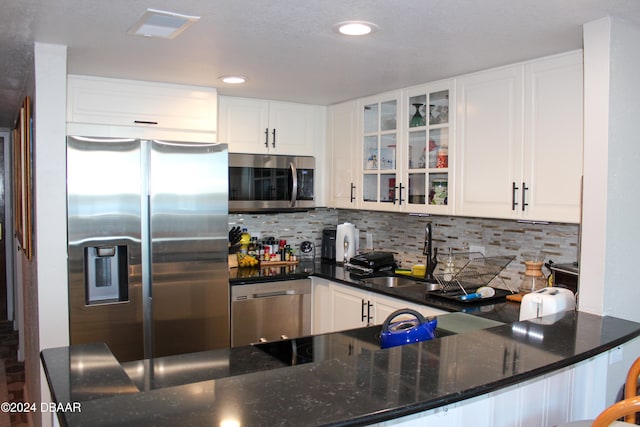 kitchen featuring decorative backsplash, dark stone counters, stainless steel appliances, sink, and white cabinets