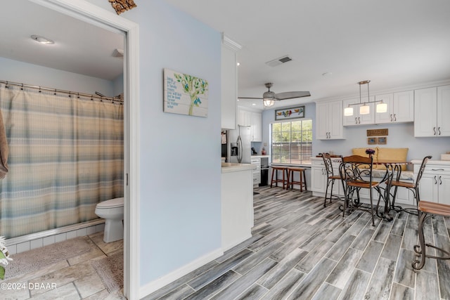 interior space with white cabinetry, ceiling fan, light hardwood / wood-style floors, and hanging light fixtures