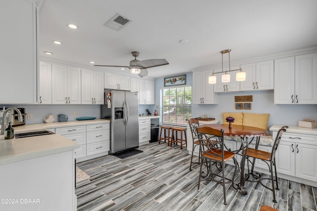 kitchen featuring stainless steel refrigerator with ice dispenser, white cabinetry, and sink