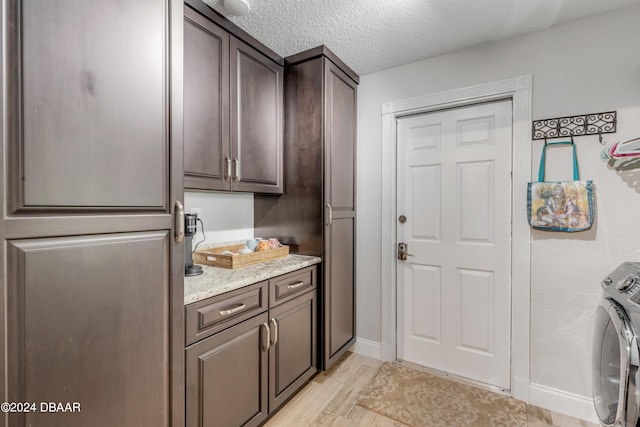 laundry room with cabinets, washer / dryer, and a textured ceiling