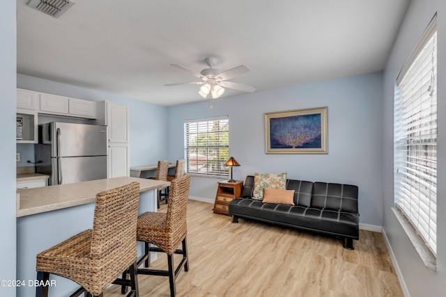 kitchen with white cabinetry, ceiling fan, stainless steel fridge, and light hardwood / wood-style floors