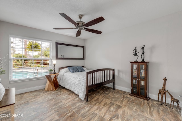 bedroom with ceiling fan and a textured ceiling