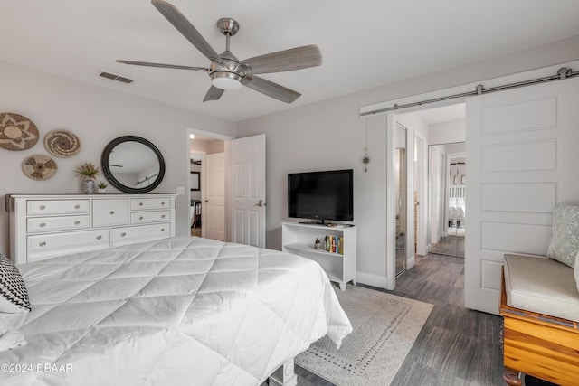 bedroom with hardwood / wood-style flooring, ceiling fan, and a barn door