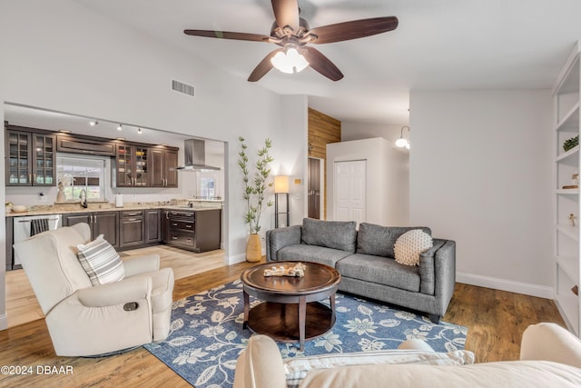 living room featuring lofted ceiling, wet bar, ceiling fan, and light wood-type flooring