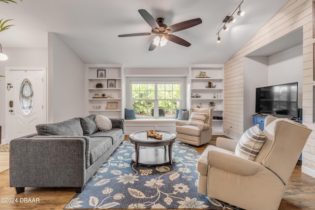 living room featuring wood-type flooring, vaulted ceiling, track lighting, built in features, and ceiling fan