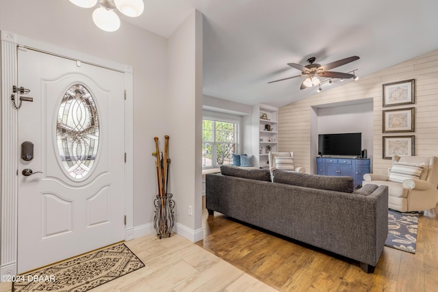 foyer entrance with lofted ceiling, ceiling fan with notable chandelier, and light hardwood / wood-style floors