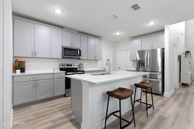 118 Pitching Wedge Dr, Daytona Beach, FL 32124 - kitchen with light wood-style flooring, stainless steel appliances, gray cabinetry, a kitchen bar, and recessed lighting