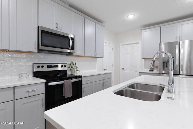 kitchen with a textured ceiling, backsplash, stainless steel appliances, and sink