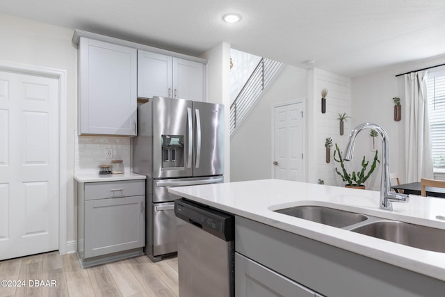 kitchen with tasteful backsplash, gray cabinetry, a textured ceiling, stainless steel appliances, and sink