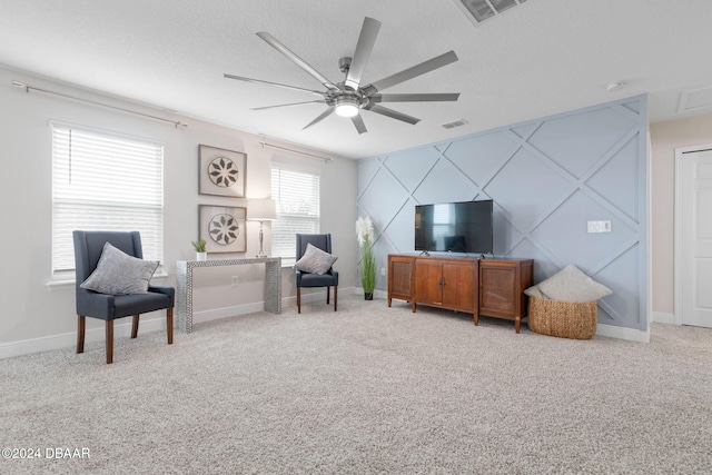 living area with a textured ceiling, ceiling fan, and light carpet