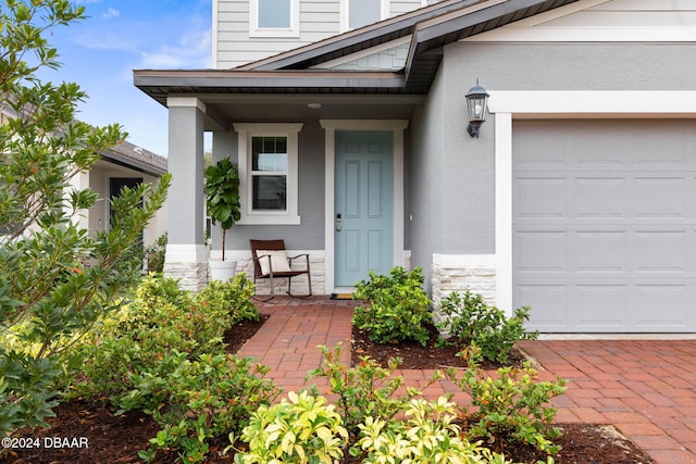 view of exterior entry with a garage and covered porch