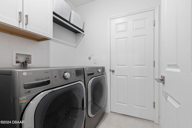 laundry area with cabinets, light tile patterned floors, and washing machine and clothes dryer