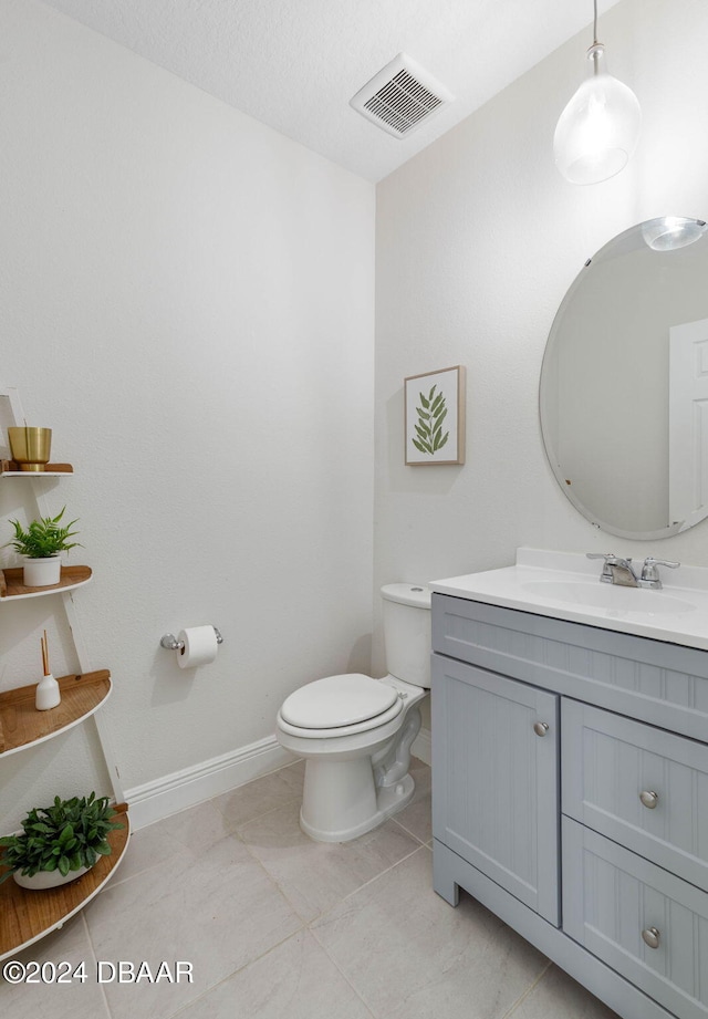 bathroom with tile patterned floors, vanity, a textured ceiling, and toilet