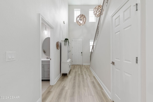 118 Pitching Wedge Dr, Daytona Beach, FL 32124 - hall featuring light wood-style flooring, a towering ceiling, stairs, and a chandelier