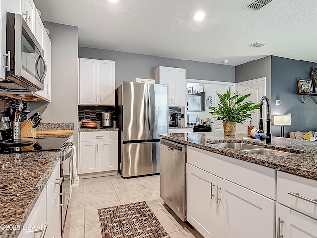 330 Charles Dr, Deland, FL 32724 - kitchen featuring appliances with stainless steel finishes, a sink, dark stone countertops, white cabinets, and a textured ceiling