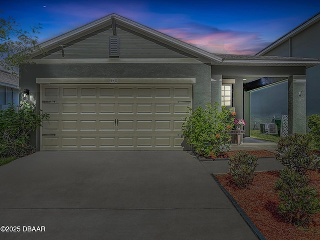 330 Charles Dr, Deland, FL 32724 - garage at dusk featuring driveway and central AC