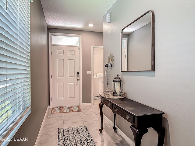 330 Charles Dr, Deland, FL 32724 - foyer entrance featuring light tile patterned flooring, washer and clothes dryer, a textured ceiling, and baseboards