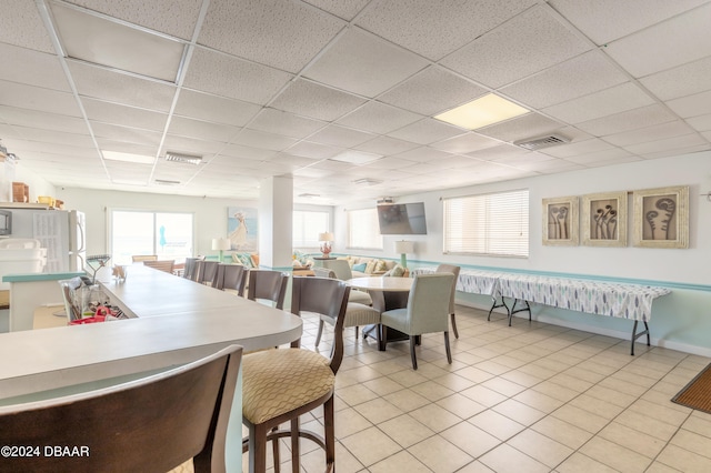 dining space with a paneled ceiling and light tile patterned floors