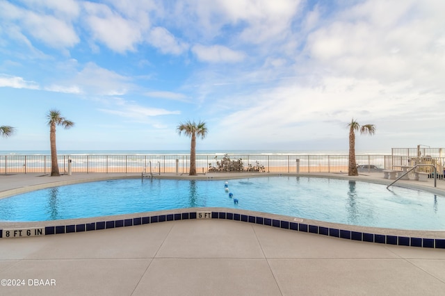 view of pool with a water view and a patio