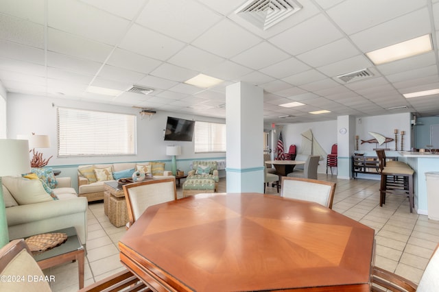 dining space with light tile patterned floors and a drop ceiling