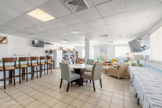 dining area featuring plenty of natural light, a paneled ceiling, and light tile patterned floors