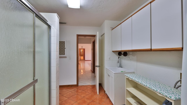 laundry room featuring sink, a textured ceiling, and light tile patterned floors