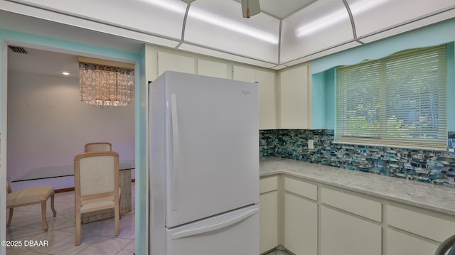 kitchen featuring white cabinetry, tasteful backsplash, light tile patterned floors, white refrigerator, and light stone countertops