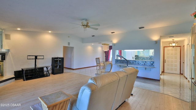 living room featuring a high end fireplace, vaulted ceiling, light hardwood / wood-style floors, and ceiling fan