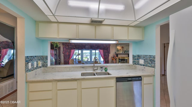 kitchen featuring dishwasher, cream cabinets, sink, and decorative backsplash