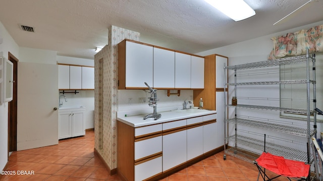 kitchen featuring sink, a textured ceiling, white cabinets, and light tile patterned flooring