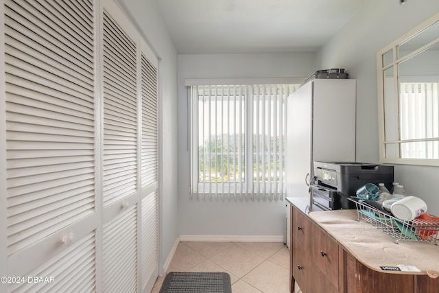 4641 S Atlantic Ave Unit 3060, Ponce Inlet, FL 32127 - kitchen featuring light tile patterned floors, baseboards, light countertops, and brown cabinetry