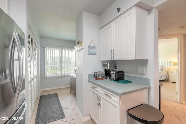 4641 S Atlantic Ave Unit 3060, Ponce Inlet, FL 32127 - kitchen featuring freestanding refrigerator, light tile patterned floors, light countertops, and white cabinetry