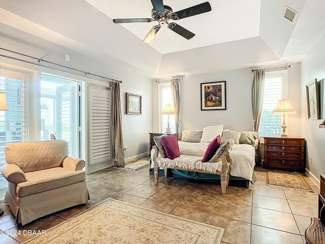 tiled bedroom with ceiling fan, access to exterior, and a tray ceiling