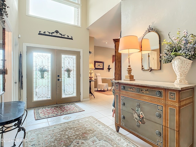 foyer with a towering ceiling, french doors, a wealth of natural light, and light tile patterned floors