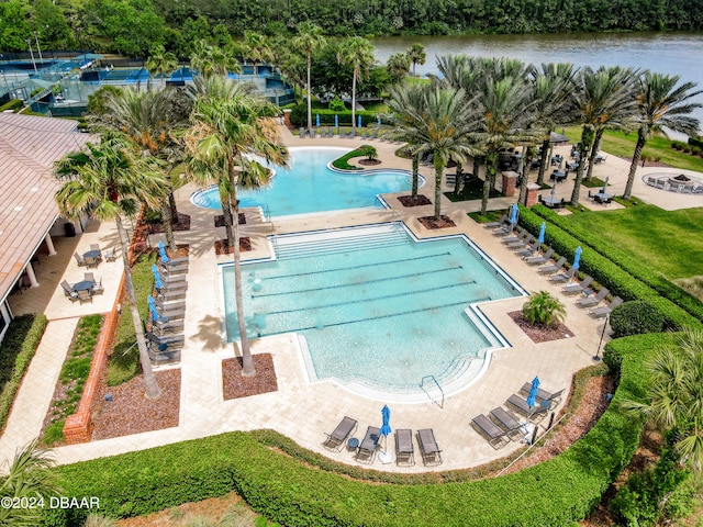 view of pool featuring a patio, a water view, and a yard