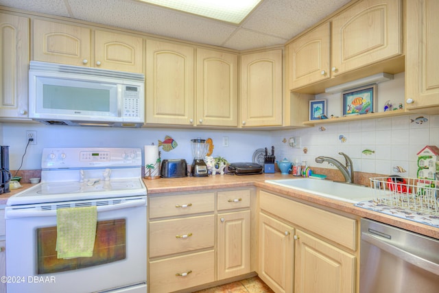 kitchen featuring light brown cabinetry, white appliances, a paneled ceiling, and sink