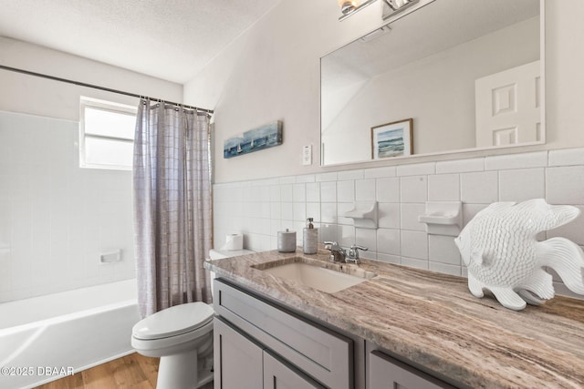 full bathroom with toilet, shower / tub combo, tile walls, a textured ceiling, and vanity