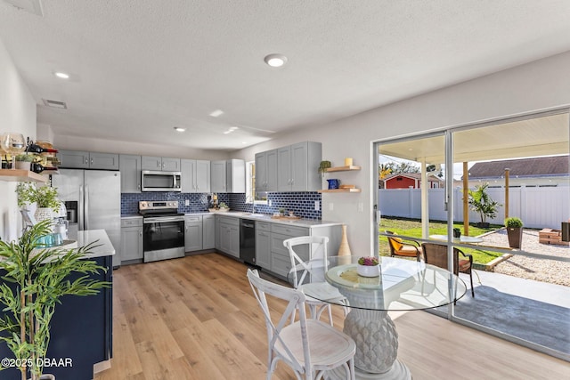 kitchen with tasteful backsplash, stainless steel appliances, sink, and gray cabinetry