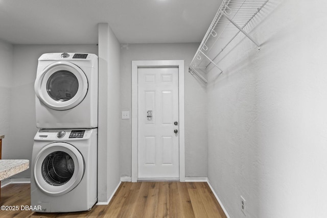 laundry area with stacked washer and dryer and hardwood / wood-style flooring