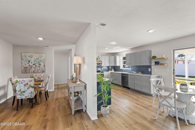 kitchen with stainless steel dishwasher, light hardwood / wood-style flooring, decorative backsplash, and gray cabinetry