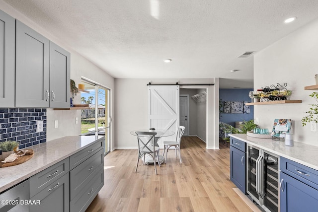 kitchen with decorative backsplash, a barn door, a textured ceiling, and light wood-type flooring